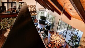 A modern interior with a wooden ceiling, a fireplace, a sofa, and a chandelier.