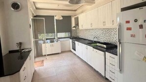 Una cocina amplia con armarios blancos, encimera negra y salpicadero de azulejos.