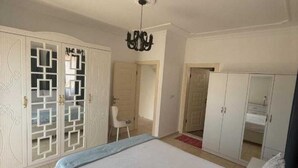 Un dormitorio con una cama grande, un armario y una silla.