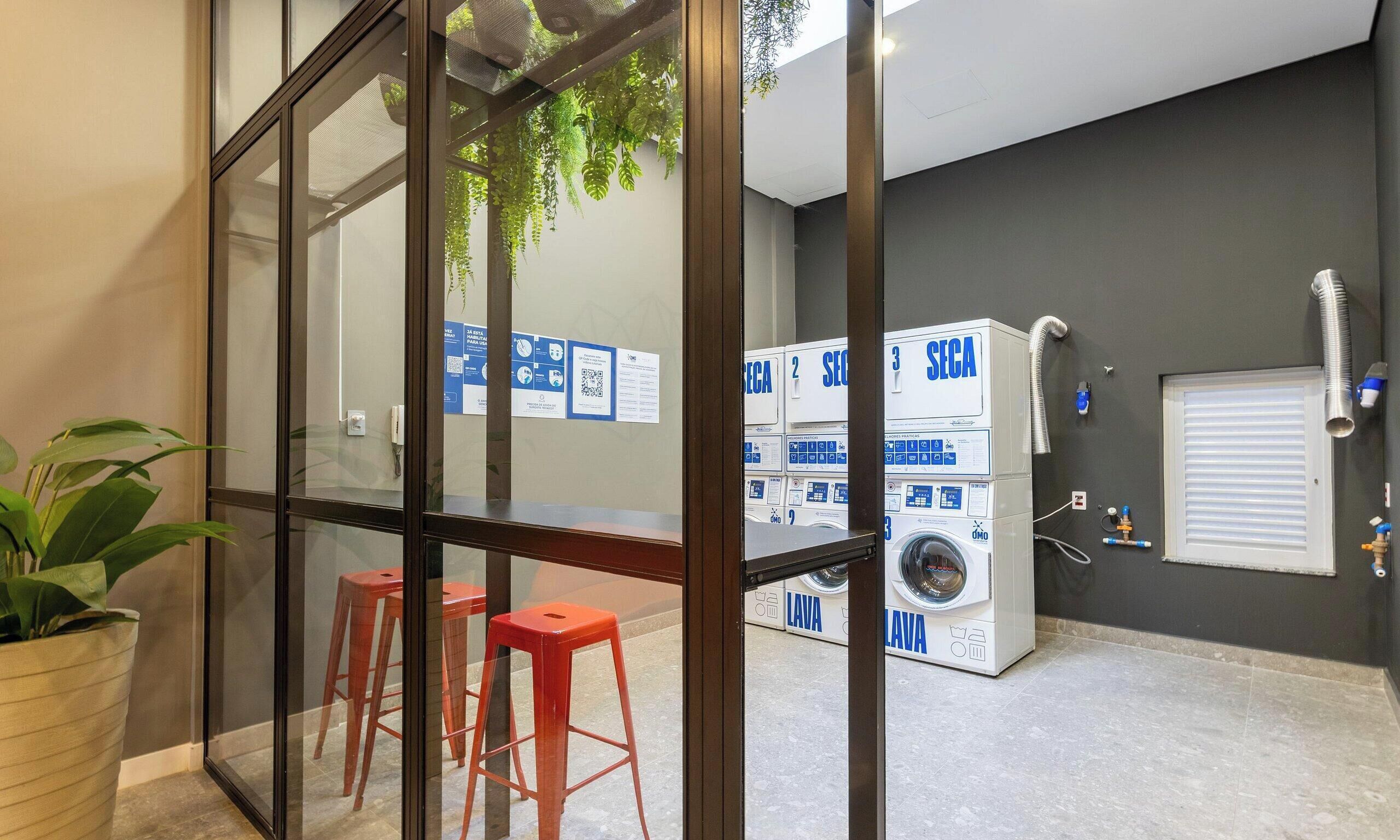 A room with a glass partition, a potted plant, and a seating area with stools.