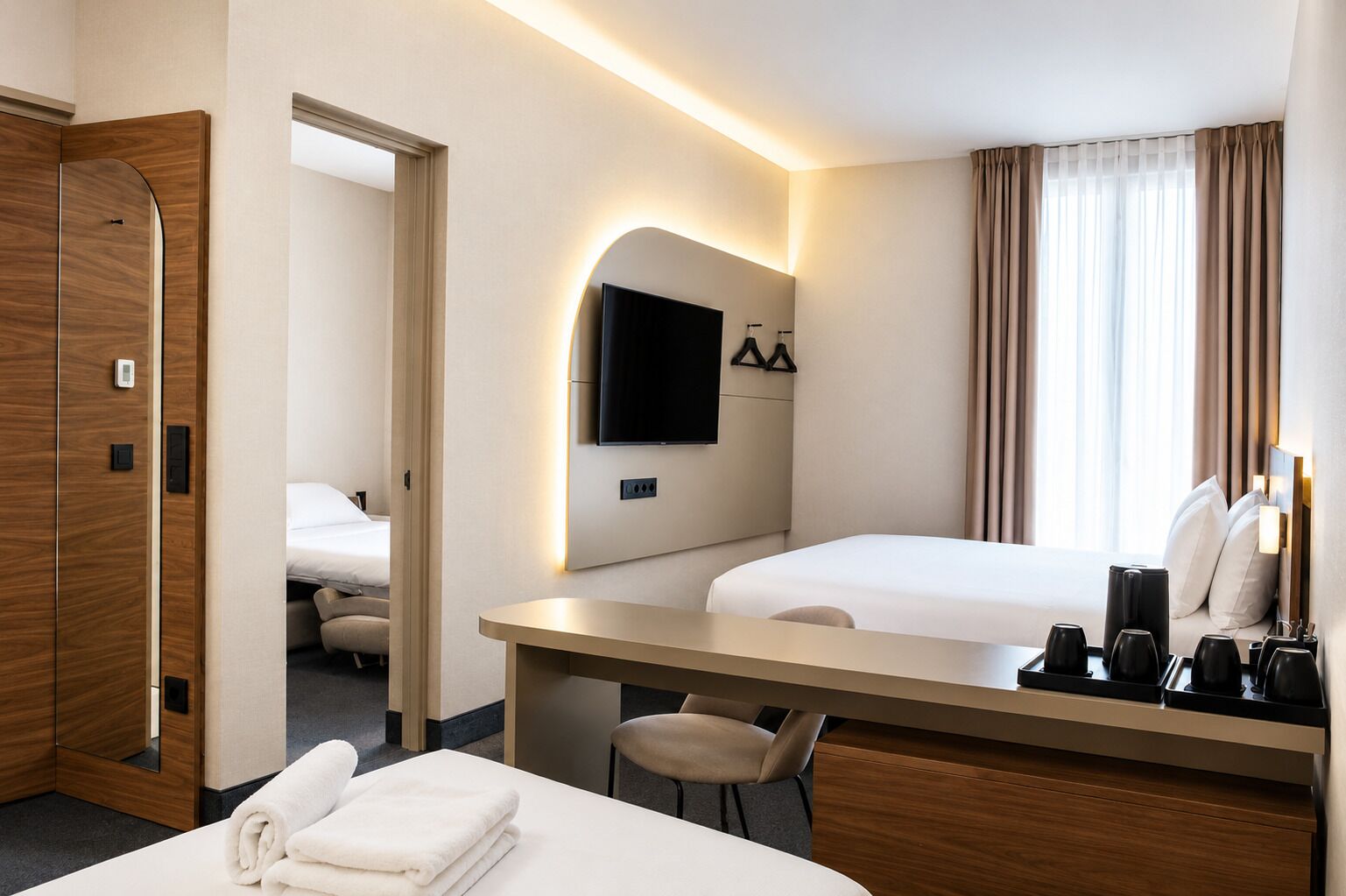 Ein Hotelzimmer mit Bett, Schreibtisch, Stuhl, Wand-Fernseher und einem Fenster mit Vorhängen.
