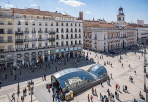 A spacious public square with a modern glass structure, surrounded by historic buildings with balconies and traditional architecture. - FORTINN Puerta del Sol (Madrid)