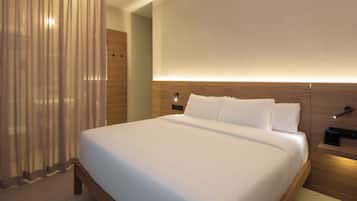 A modern hotel room with a large bed, wooden headboard, and a bedside table with a lamp.