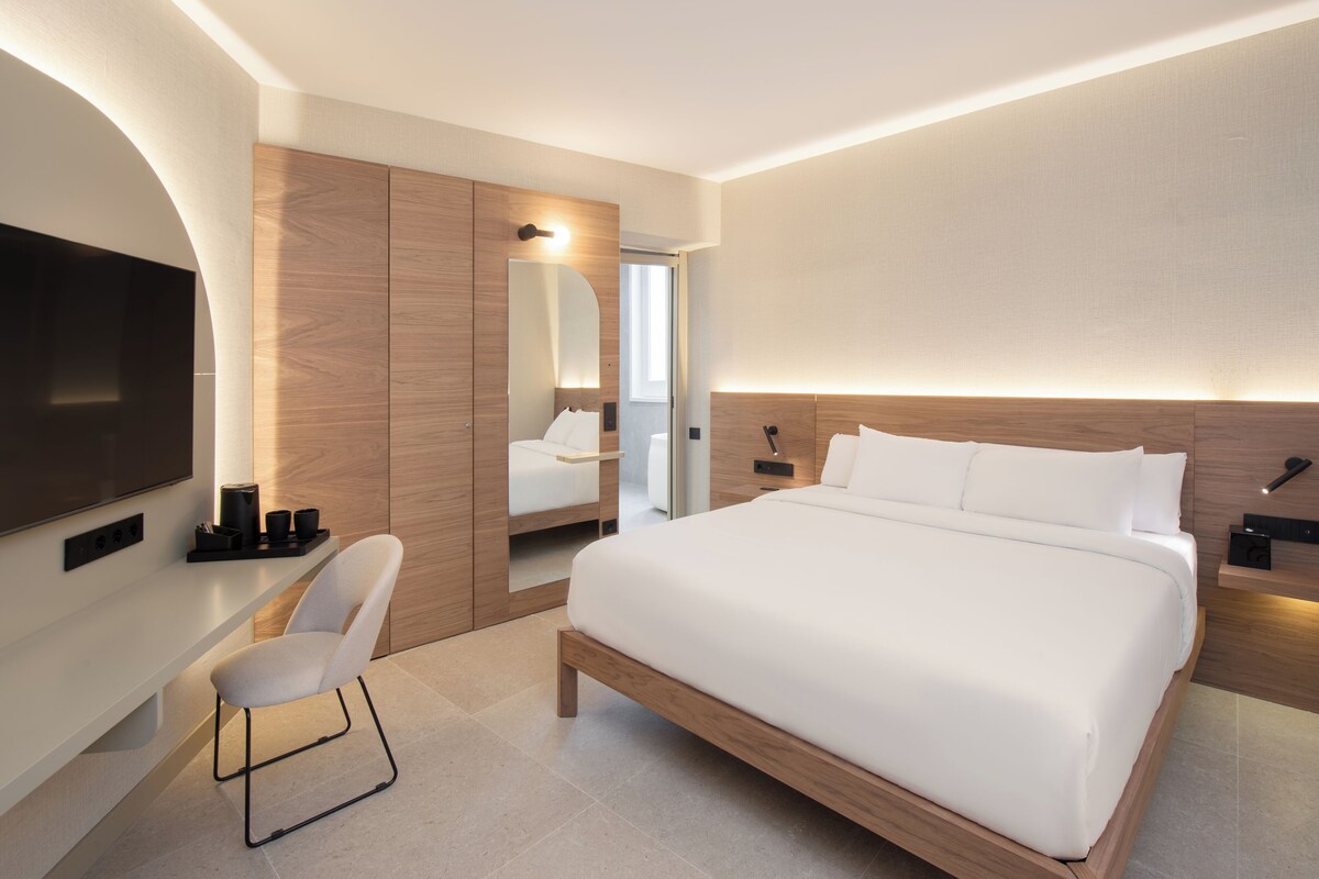 Een moderne hotelkamer met een groot bed, een flatscreen televisie, een zithoek en een inloopkast.