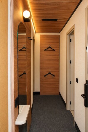 Un pasillo con paneles de madera, un espejo, un banco y una puerta.