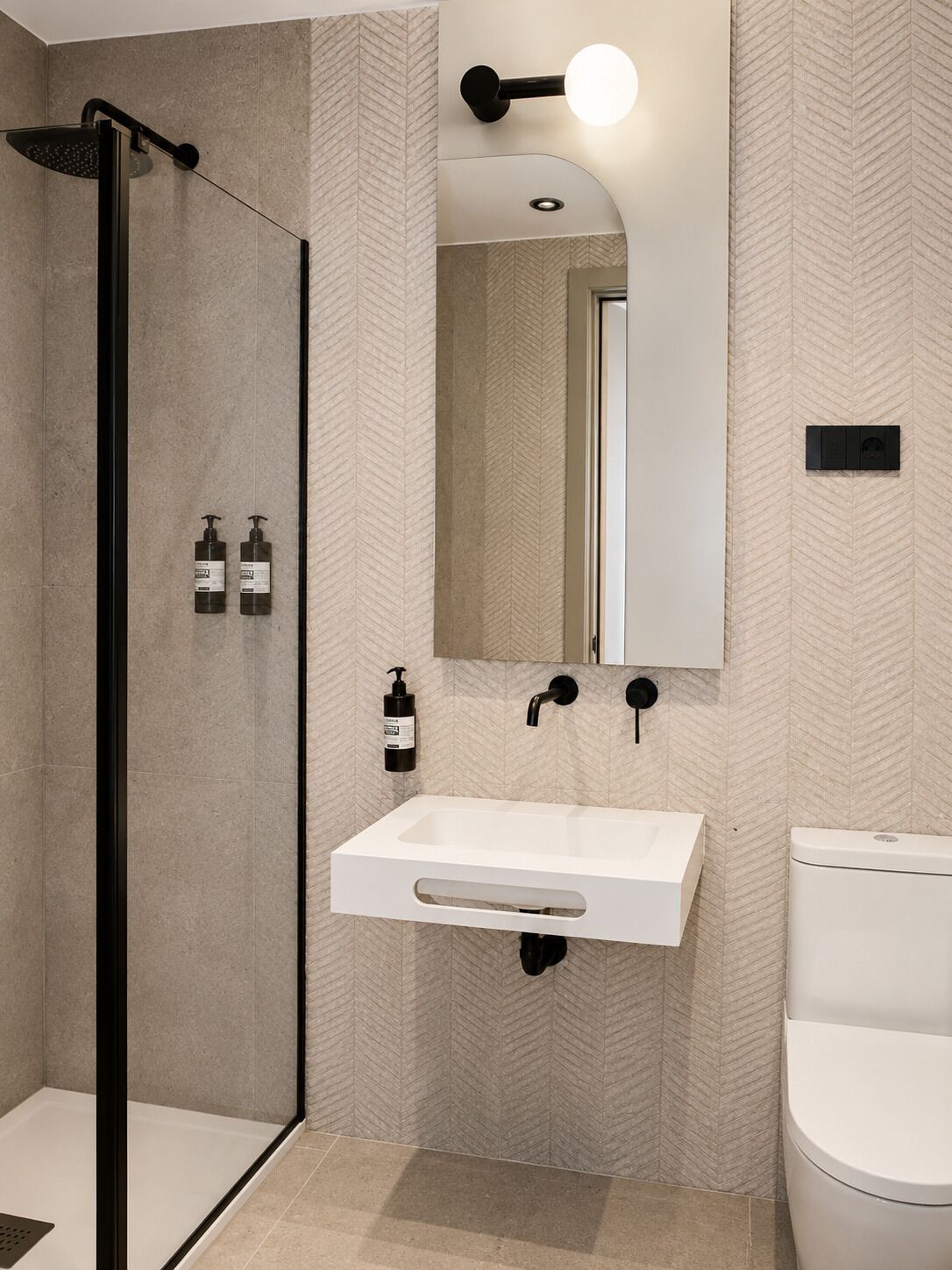 Ein modernes Badezimmer mit Dusche, Waschbecken, Toilette und einem Spiegel mit Leuchte.