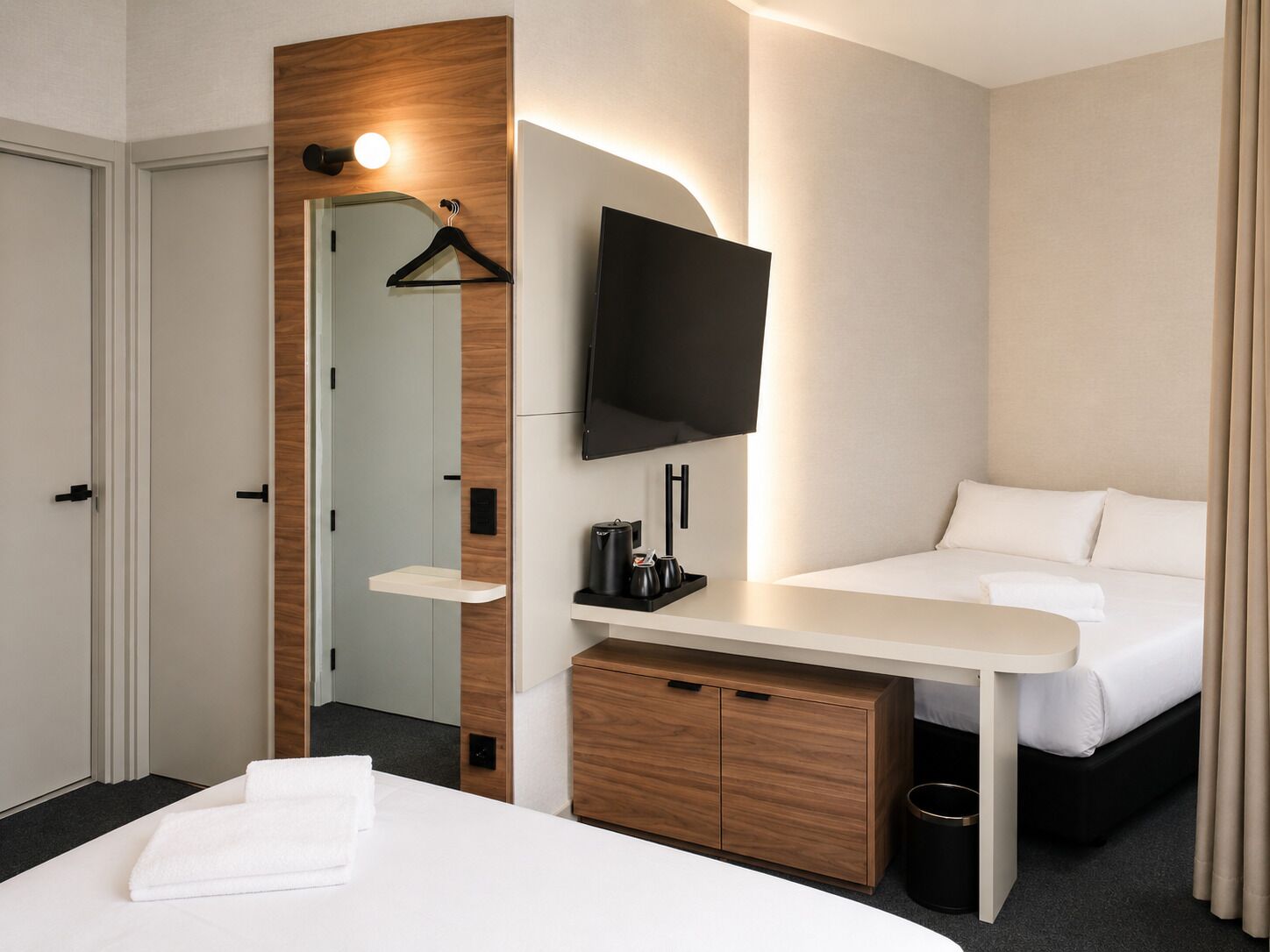 A hotel room with a bed, bedside table, TV, wooden cabinet, and a mirror.
