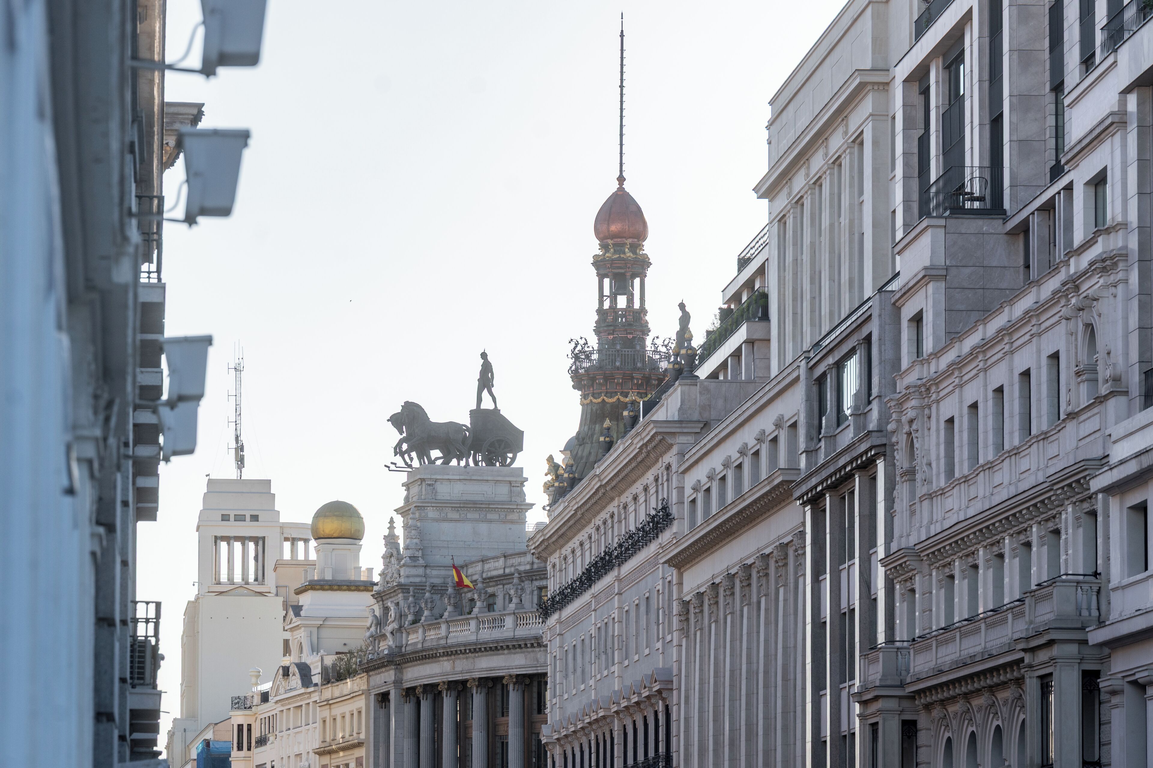 Vista de una calle con arquitectura clásica, que incluye fachadas ornamentadas y estatuas.