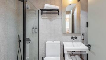 Un baño moderno con ducha acristalada, un lavabo blanco y un espejo sobre él.