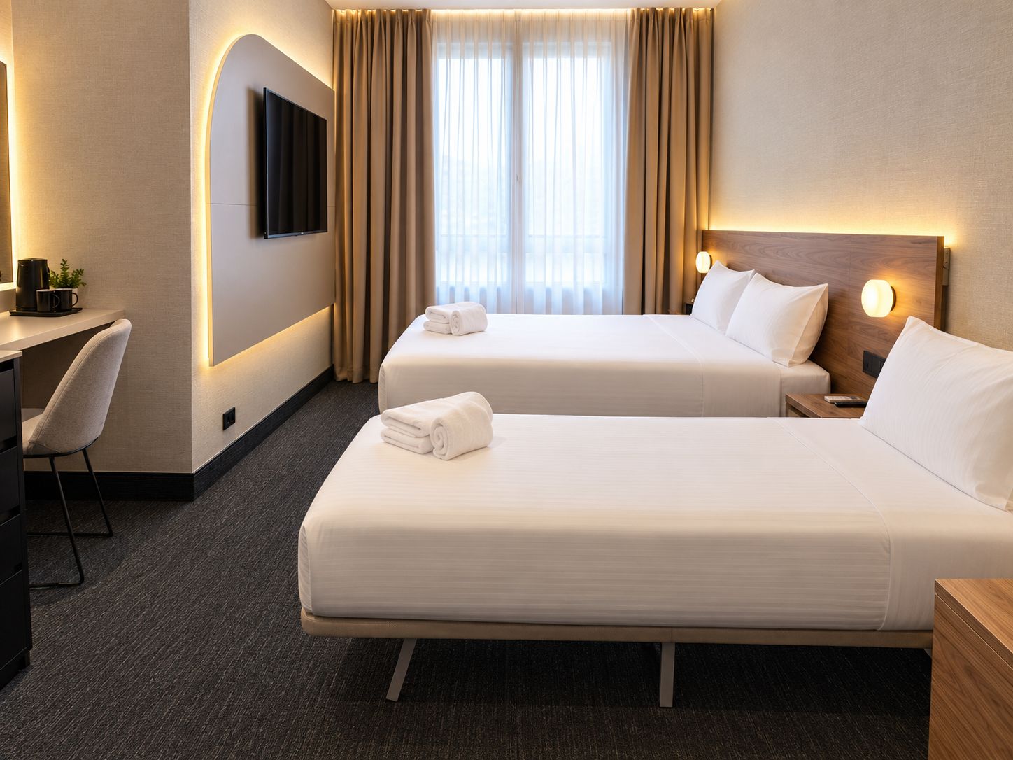 Een hotelkamer met twee bedden, een bureau, een stoel en een televisie aan de muur.