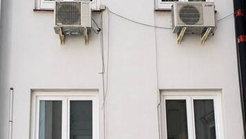 A building with four windows, each with an air conditioning unit attached.