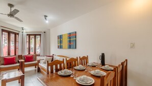 Ein Essbereich mit einem Holztisch, gedeckt für vier Personen, einem Deckenventilator und einem farbenfrohen, abstrakten Gemälde an der Wand.