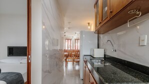 Eine kleine Küche mit Kühlschrank, Spüle und Holzschränken.