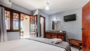 Ein Schlafzimmer mit einem Bett, einem Schminktisch mit Spiegel, einem Flachbildfernseher und einer Holztür.