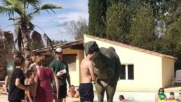 Un espace autour d’une piscine, avec une grande statue d’éléphant, et de nombreuses personnes rassemblées autour.