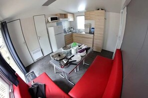 A compact kitchen with a dining area, equipped with a microwave, refrigerator, and a sink.