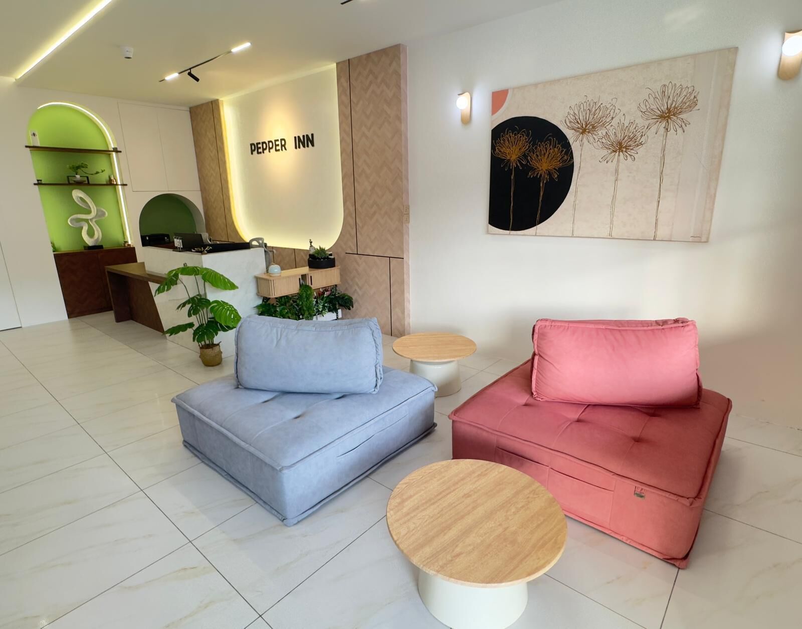 Un interior moderno con una recepción, un sofá azul y rosa, una pequeña mesa de madera y una obra de arte en la pared.