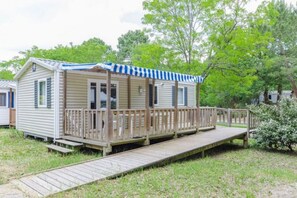 Une maison mobile dotée d’une véranda, d’une terrasse et d’une petite rampe d’accès.