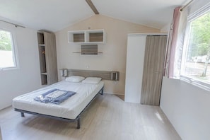 Une chambre à coucher comprenant un lit, une armoire, une étagère et une fenêtre.