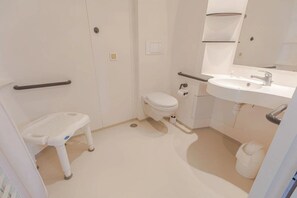 Une petite salle de bain moderne, équipée de toilettes, d’un lavabo et d’un petit marchepied.