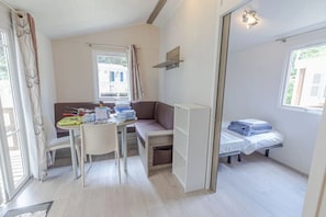 A compact room with a kitchenette, a dining area, and a bed.