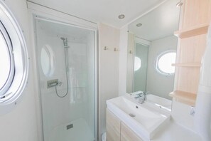 Une salle de bain moderne avec une douche à parois de verre, un lavabo blanc et un grand miroir.