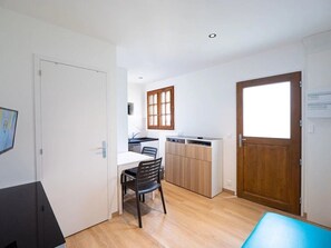 Una cocina compacta con zona de comedor, armarios de madera y un amplio ventanal.