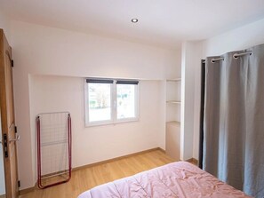 Un dormitorio con cama, ventana, tendedero y cortina.
