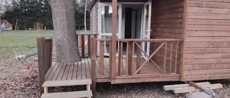 Una pequeña cabaña de madera con un porche y unos escalones que llevan a la puerta.