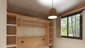 Ett kompakt sovrum med en våningssäng, inbyggda hyllor och ett stort fönster med utsikt över träd.