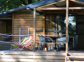 Une terrasse en bois avec des meubles d’extérieur, notamment des chaises et une table.
