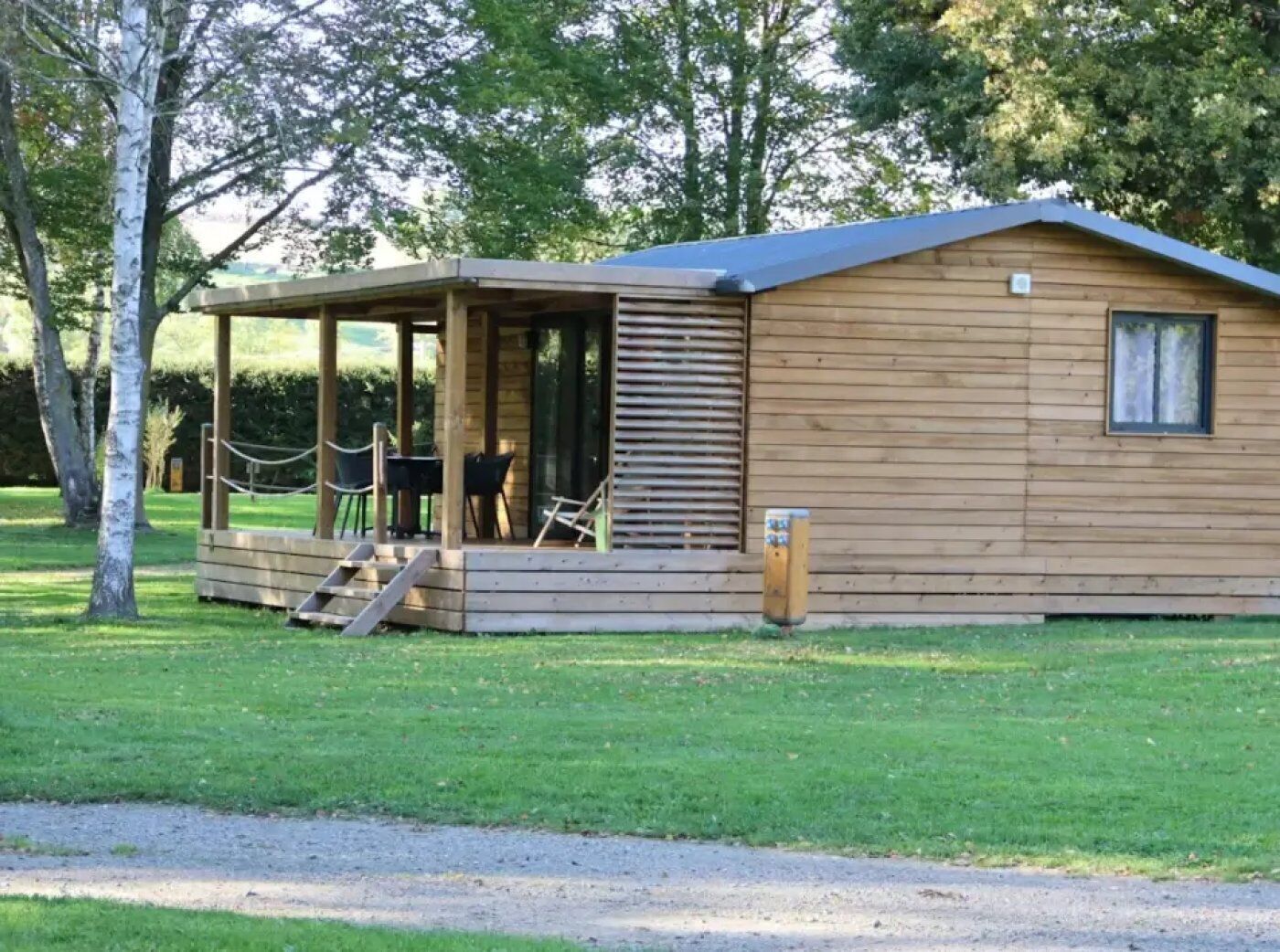 A wooden cabin with a covered porch, a small table, and chairs.