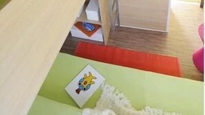 A compact room with a bunk bed, a ladder, and a small desk area.