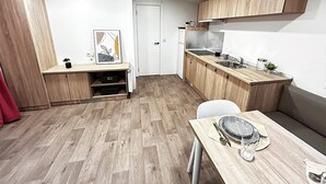 Una cocina compacta con armarios de madera, una mesa de comedor y una pequeña zona de estar.