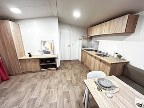 A compact kitchen with wooden cabinets, a dining table, and a small seating area.