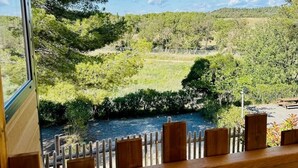Una terraza de madera con vista a un río y colinas boscosas.