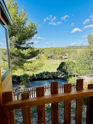 A wooden deck with a view of a river and forested hills.