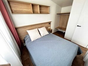 Une chambre à coucher comprenant un lit, une tête de lit en bois, des tables de chevet et des étagères intégrées.