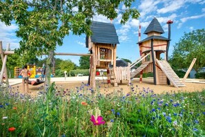 Een speeltuin met houten speeltoestellen en een glijbaan.