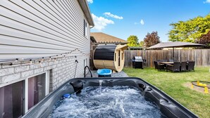 Ein Garten mit Whirlpool, Holzterrasse und Gartenmöbeln.