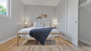 Ein Schlafzimmer mit einem hölzernen Bett, weißen Wänden und einem Fenster.