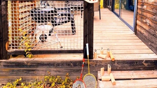A wooden deck with a pergola, a fenced area with a hat on a post, and a table with numbered sticks.