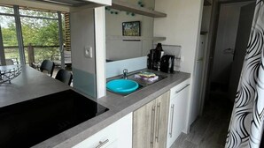 A modern kitchen with a black stove, a blue sink, and white cabinets.