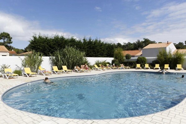 A swimming pool with yellow lounge chairs and a tiled deck.
