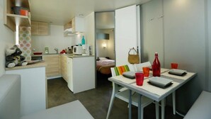 A compact hotel room with a kitchenette, a dining area, and a bed.
