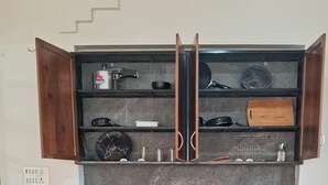 Een keukenkast met meerdere planken, vol met verschillende keukengerei en pannen.