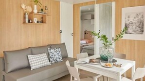 A modern living room with a grey sofa, a white table, and a vase with plants.