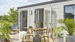 A modern outdoor patio with a wooden deck, a table with chairs, and potted plants.