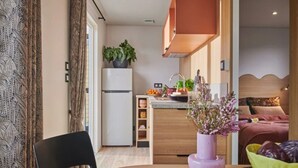 A compact living space with a kitchenette, a dining area, and a bedroom.