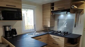 Una cocina compacta equipada con microondas, cafetera y estufa.